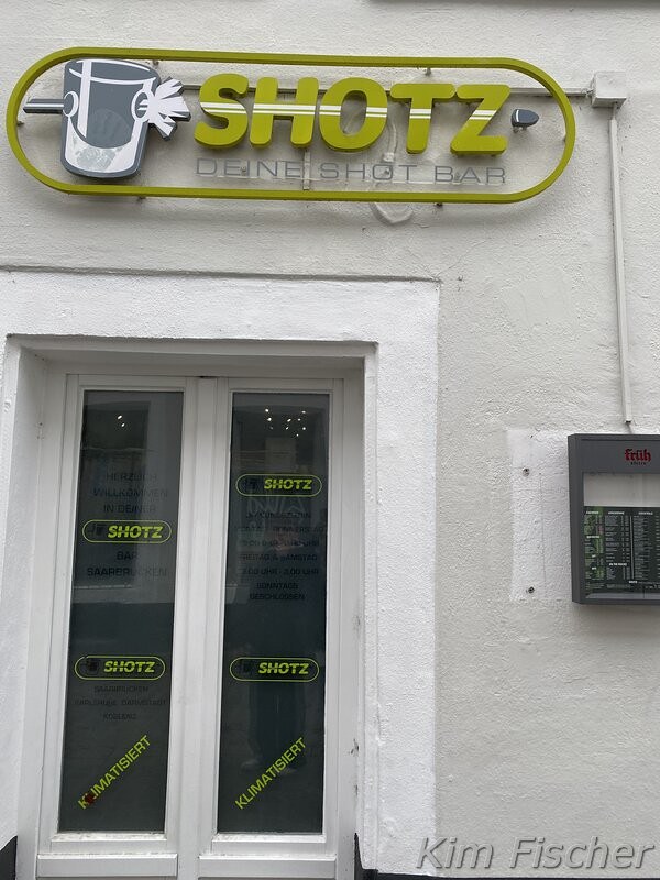 Here you can see the entry of the bar „Shotz“. The windows are decorated with Shotz-stickers and on the wall on the left side is the shot-menu
